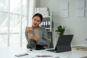 Asian woman, independent businesswoman, feeling stressed, achy, and sleepy while working on a laptop. Tired Asian businesswoman has a headache at the office Feeling sick at work.