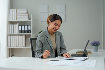 Young Asian businesswoman uses a calculator to calculate business principles. Accounting statistical concepts at the office starting a financial business, calculating accounting online marketing.
