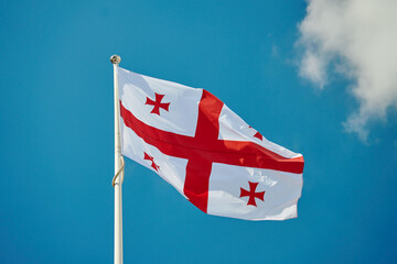 National flag of Georgia waves against bright blue sky