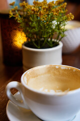 Empty cappuccino cup with frothy remnants, set on wooden table. Breakfast in cozy cafe in the morning