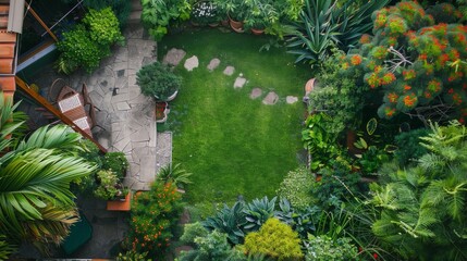 An aerial view of a vibrant backyard garden with a stone pathway leading to a lush green lawn and a patio area