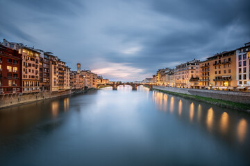 One of the most beautiful view of Florence: Ponte Santa Trinita taken from Ponte Vecchio with street lights the historical houses reflected in the Arno river just after the sunset