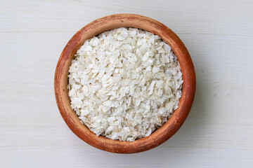 Flattened rice or chira on a earthen pot on a wooden background. It is also known as poha, pohe, aval, pauwa, sira, chivda, or avalakki.