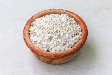 Chira or flattened rice on a earthen pot on a wooden background. It is also known as poha, pohe, aval, pauwa, sira, chivda, chiwda, or avalakki.