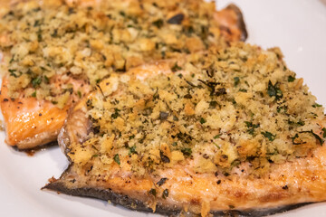 Baked salmon with bread crumbs garlic and parsley on white plate