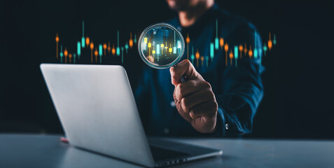 businessman or trader's hand holds a magnifying glass focused on a virtual stock market graph chart, symbolizing stock trading and investing concepts. This encompasses foreign exchange, trading funds