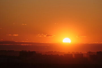 The sunset cast a red glow on the clouds above the evening city skyline with its tall rooftops, time lapse.