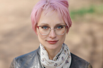 close-up portrait of young beautiful caucasian woman with coloured pink hair in park smiling