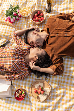 Happy young couple lying face to face on picnic blanket with each other