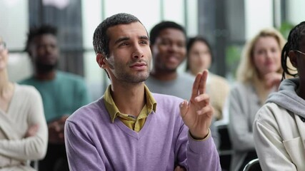 Young businessman sitting listening to trainer speaking to audience