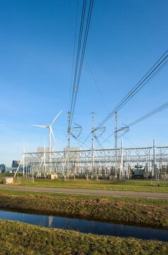 Wind turbines near power lines and transformator substation under blue sky