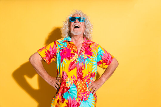 Fototapeta Cheerful senior man wearing sunglasses and standing with hands on hips against yellow background