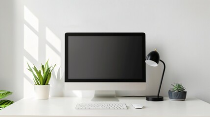 A minimalist workspace with a clean white desk, a single monitor, a small succulent plant, and a simple desk lamp
