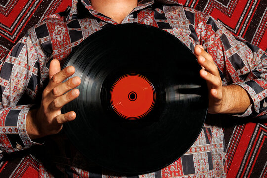 Man lying on back and holding record over abstract background
