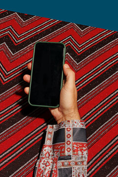 Hand of man holding smart phone against abstract background