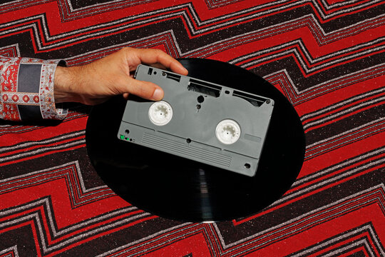 Hand of man holding videocassette against patterned background