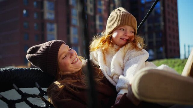 Mother And Daughter Swinging On Playground In Spring