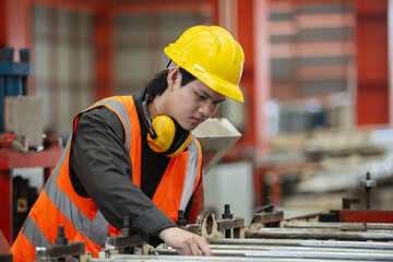 Asian male workers wear red helmet working check up iron production manufacturing in factory. Foreman in heavy Industrial workplace.