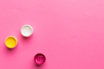 jars with gouache of different colors on Colored background. hobby painting. Top view with empty space. workplace for creativity. home teaching concept drawing