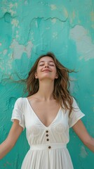 A young woman wearing a white dress leaning against the wall