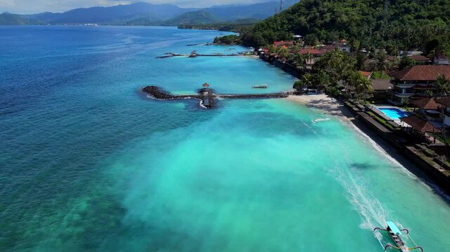 Beach fromt of Candidasa in Bali showing the clear blue water and wave breakers to stop erosion of the beaches