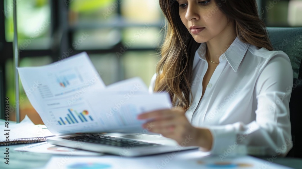 Poster a businesswoman focused on data charts for insights and patterns at her desk in a professional setti