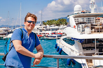 A man is waving on a yacht with a sunny harbor background, enjoying summer travel by the seaside