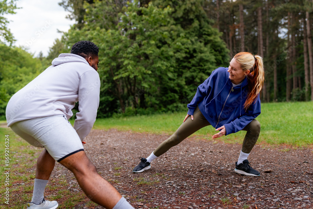 Canvas Prints A couple stretching and preparing for a jog in the forest. They are smiling and dressed in sportswear, enjoying the outdoor activity.