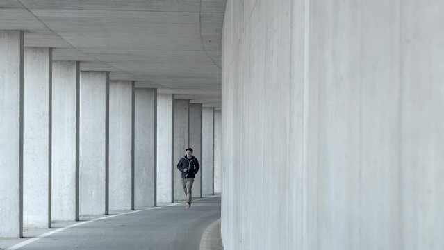 Man running along a concrete wall in an underpass