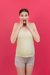 Young surprise or shocked woman pregnant isolated colored background. expression female