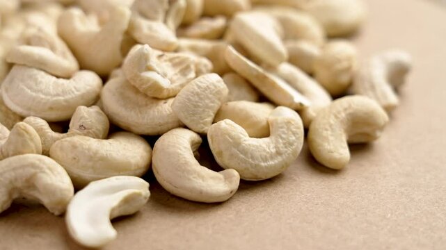 Group of raw cashew nuts with creamy color and natural texture on a brown background close up. Rotation