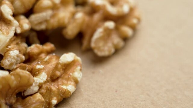 Chef hand takes raw shelled walnuts on a brown surface. Organic nuts close up
