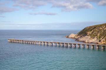 Obraz premium Jetty, a long wooden pier extending into the sea against a blue sky