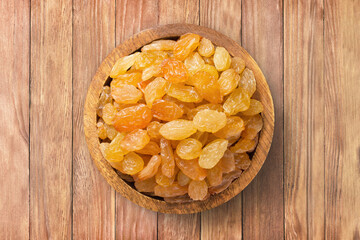 golden raisins in bowl on wooden table background, top view. organic vegetarian food.
