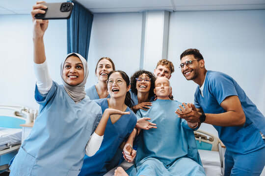 Celebrating a successful training: Diverse nursing class takes selfie with a dummy in simulation centre