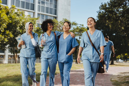 Female medical student in scrubs walking together on campus after class