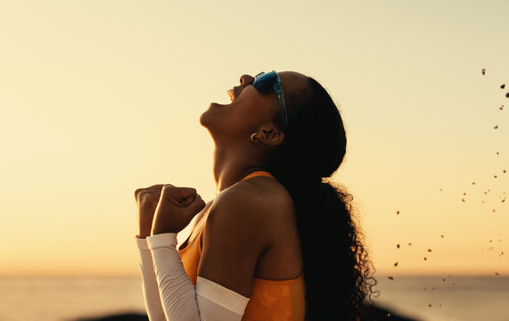 Young woman celebrating victory on the beach volleyball court at sunset
