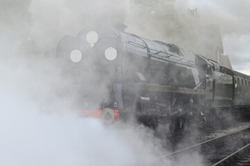 Battle of Britain Class steam locomotive smoking at a station in the UK. 