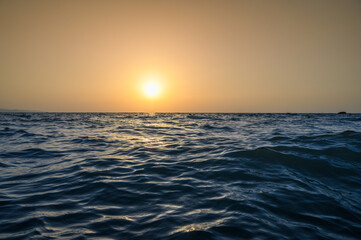 Warm waves of the Mediterranean sea and a sandy beach at sunrise