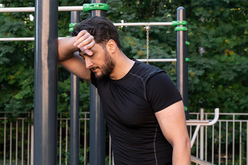 Obraz premium Young athletic man gets very tired while working out outdoors