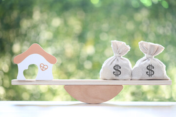 Home loan,Model house and money bag on wood scale seesaw on natural green background, Business...