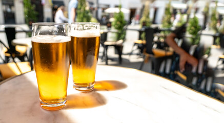 Beer glass in sunny day, cold pint glass with remaining beer on outdoor table, cool condensation