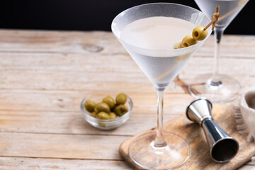 Vodka martini cocktail with vodka and vermouth and green olives on wooden table. Copy space