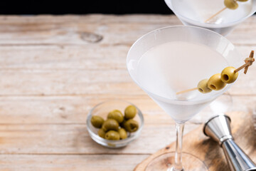 Vodka martini cocktail with vodka and vermouth and green olives on wooden table. Copy space
