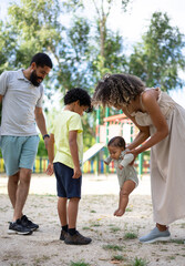 Latin family in a playground with their two children. Family of father, mother, child and baby