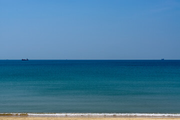 浜に白波寄せる海の沖に島と船影20240614