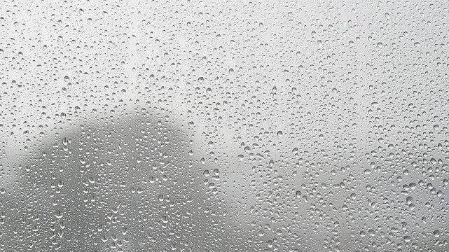 rain falling, raining outside window, focus on drops on window, summer rain in gloomy day in city