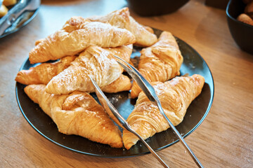 A pile of croissants on a dark plate. Sprinkle a little powdered sugar on top. Self-service restaurant