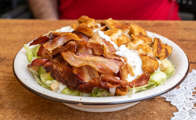 Polish Caesar salad with chicken, bacon and vegetables, high-calorie meat salad with fresh vegetables