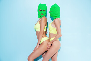 Two beautiful sexy women in green underwear. Models wearing bandit balaclava mask. Hot seductive...